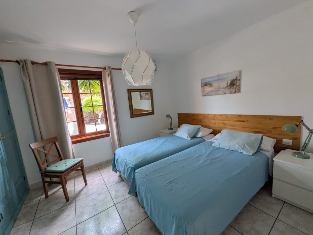 Habitación luminosa con dos camas y vista a la ventana en Casas del Sol.