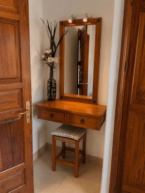 Mirror and wooden countertop in a room with floral decoration and a wooden chair.